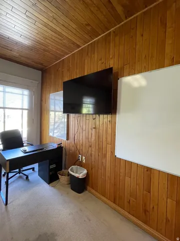 Carpeted home office featuring wooden walls and wooden ceiling