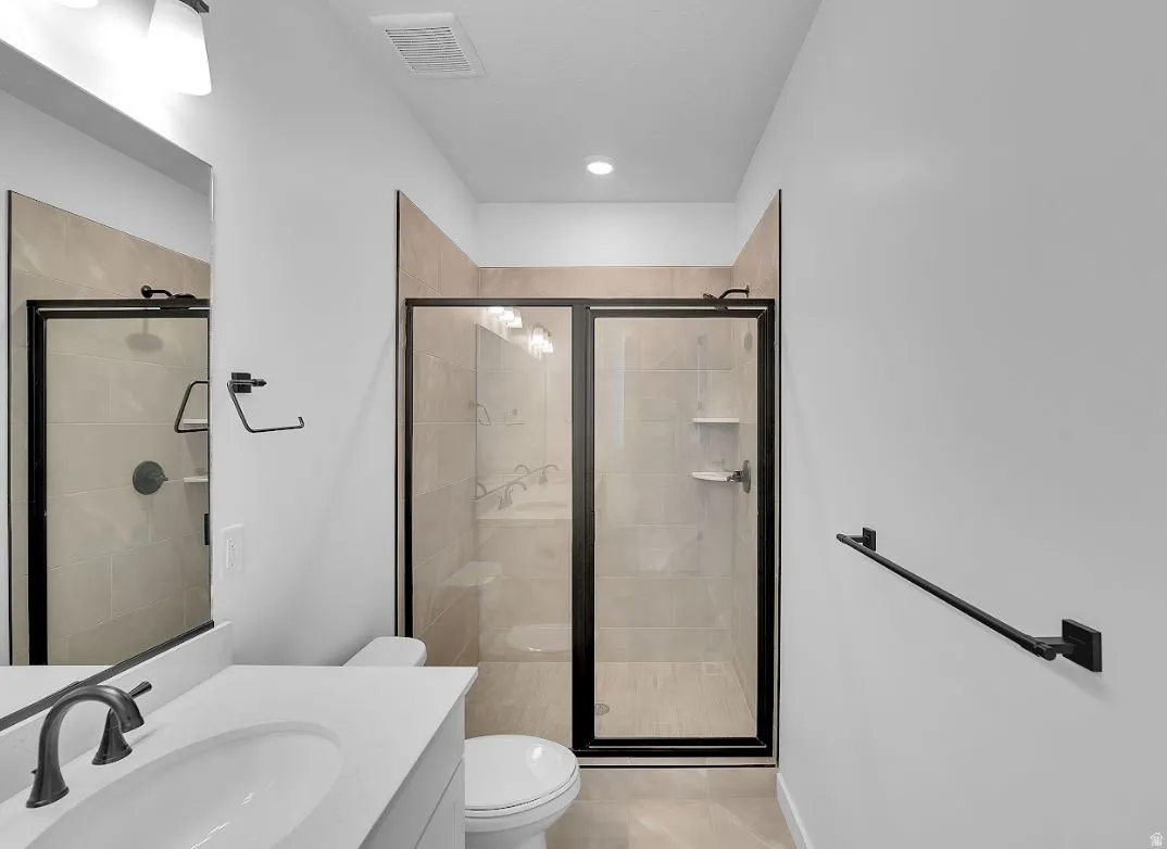 Full bathroom featuring vanity, a stall shower, and light tile patterned floors