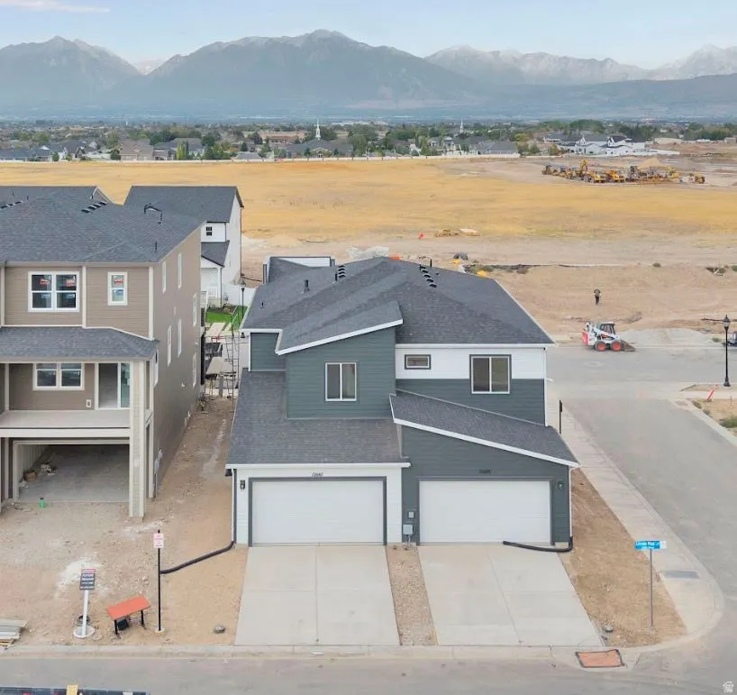 View of front of property featuring a mountain view, a residential view, an attached garage, concrete driveway, and roof with shingles