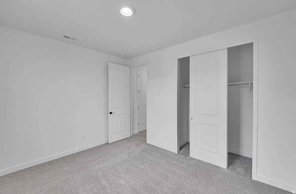 Unfurnished bedroom with light colored carpet and a closet