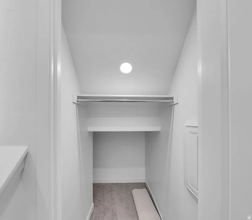 Walk in closet with vaulted ceiling and light colored carpet