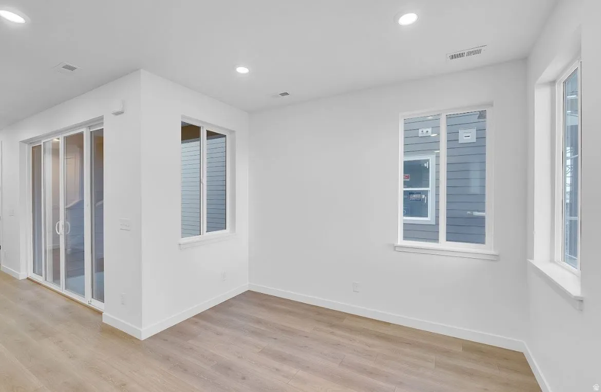 Empty room featuring light wood finished floors, recessed lighting, and plenty of natural light