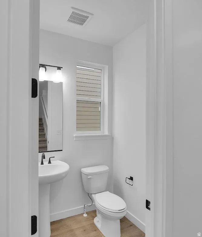 Half bathroom featuring toilet and light wood-style floors