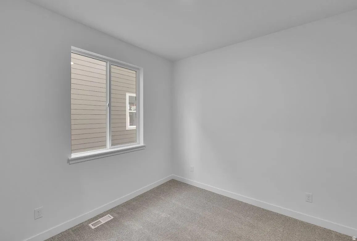 Spare room featuring baseboards and light carpet