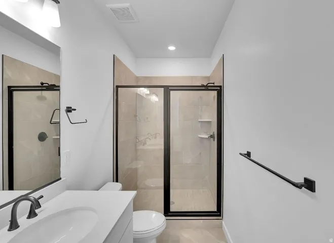 Full bathroom featuring vanity, a stall shower, and light tile patterned floors