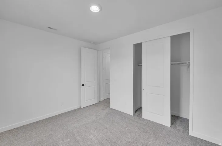 Unfurnished bedroom with light colored carpet and a closet