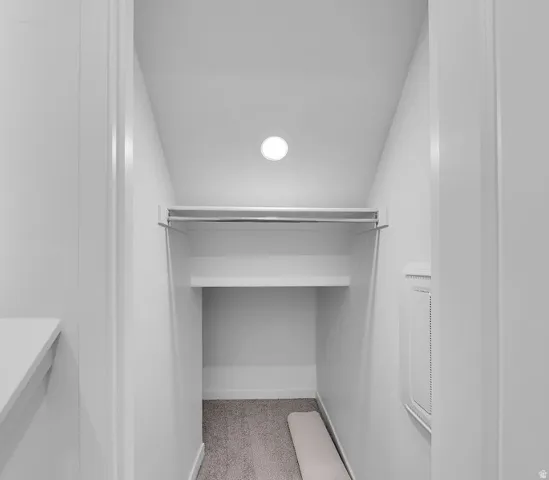 Walk in closet with vaulted ceiling and light colored carpet