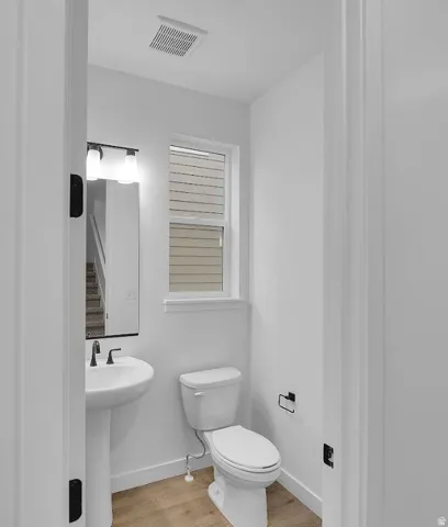 Half bathroom featuring toilet and light wood-style floors
