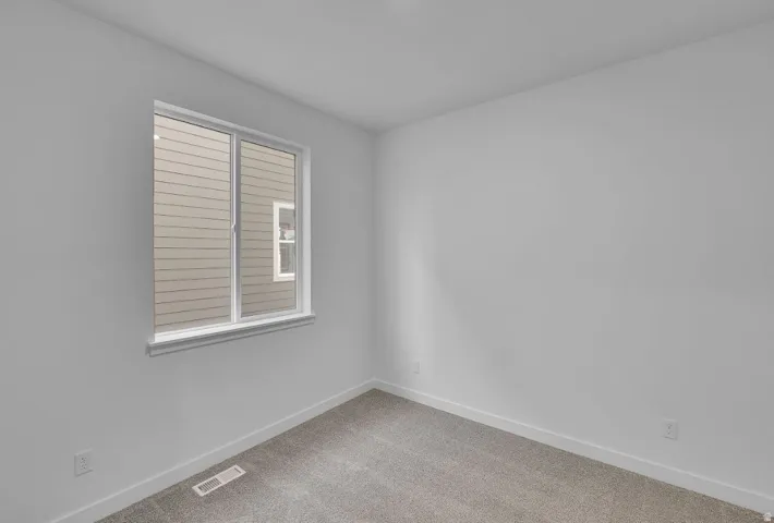 Spare room featuring baseboards and light carpet