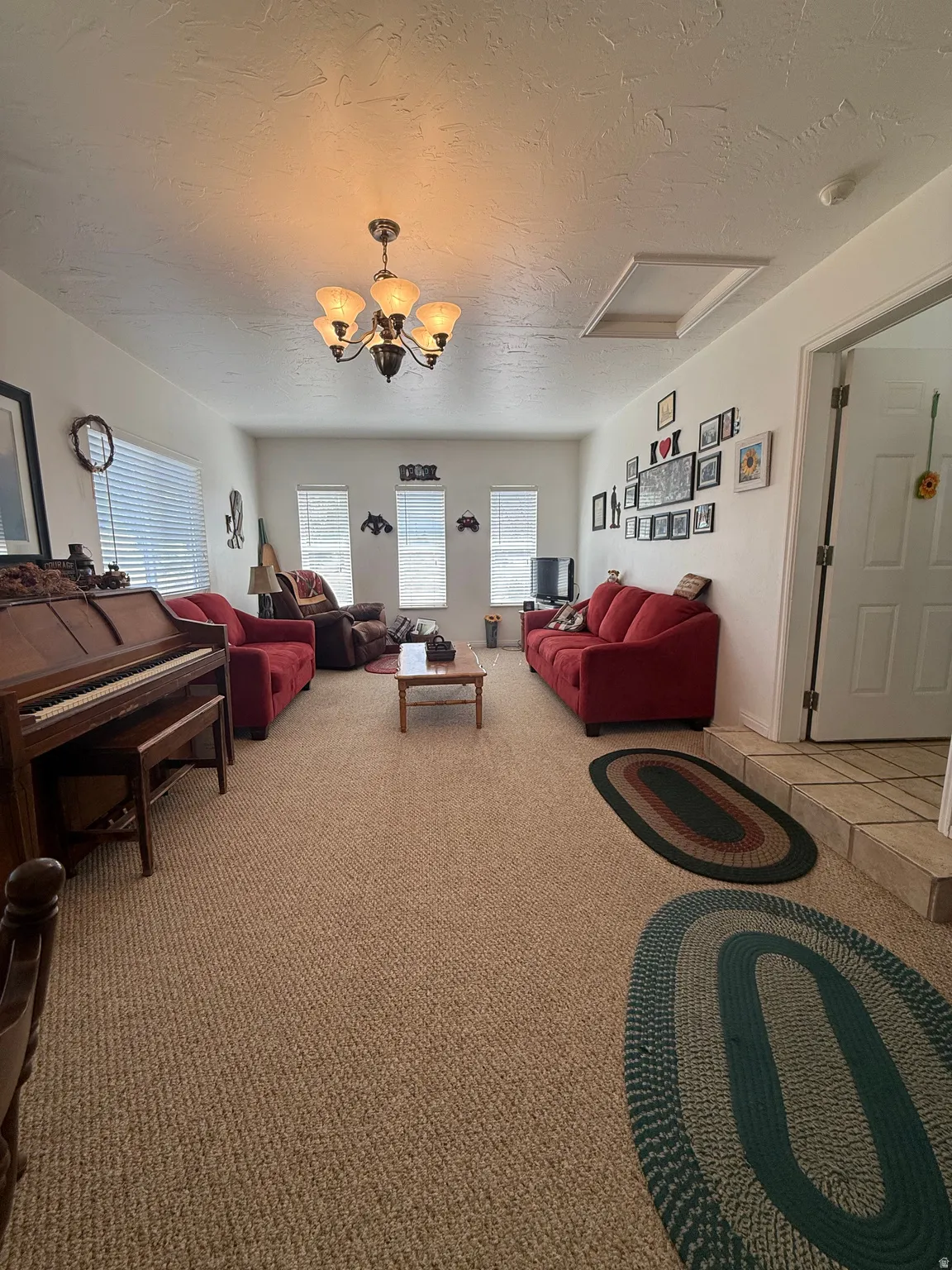 Living room featuring carpet flooring, a textured ceiling, and a chandelier