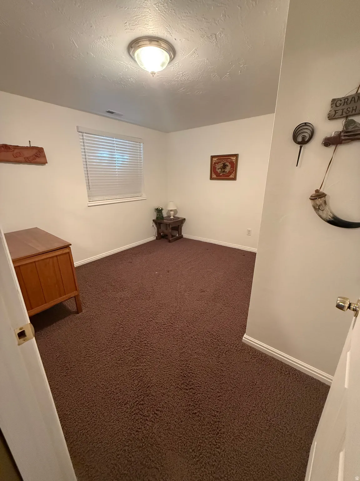 Spare room featuring dark colored carpet and a textured ceiling