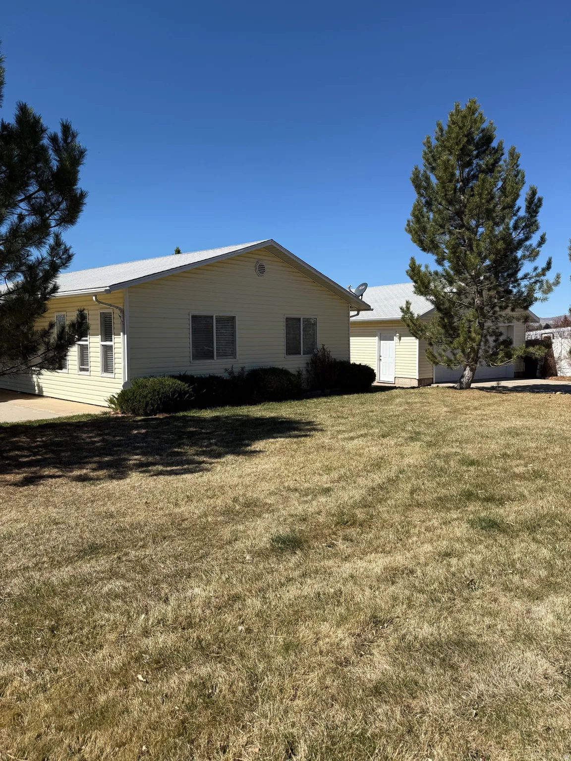 View of side of home with a yard and a shed
