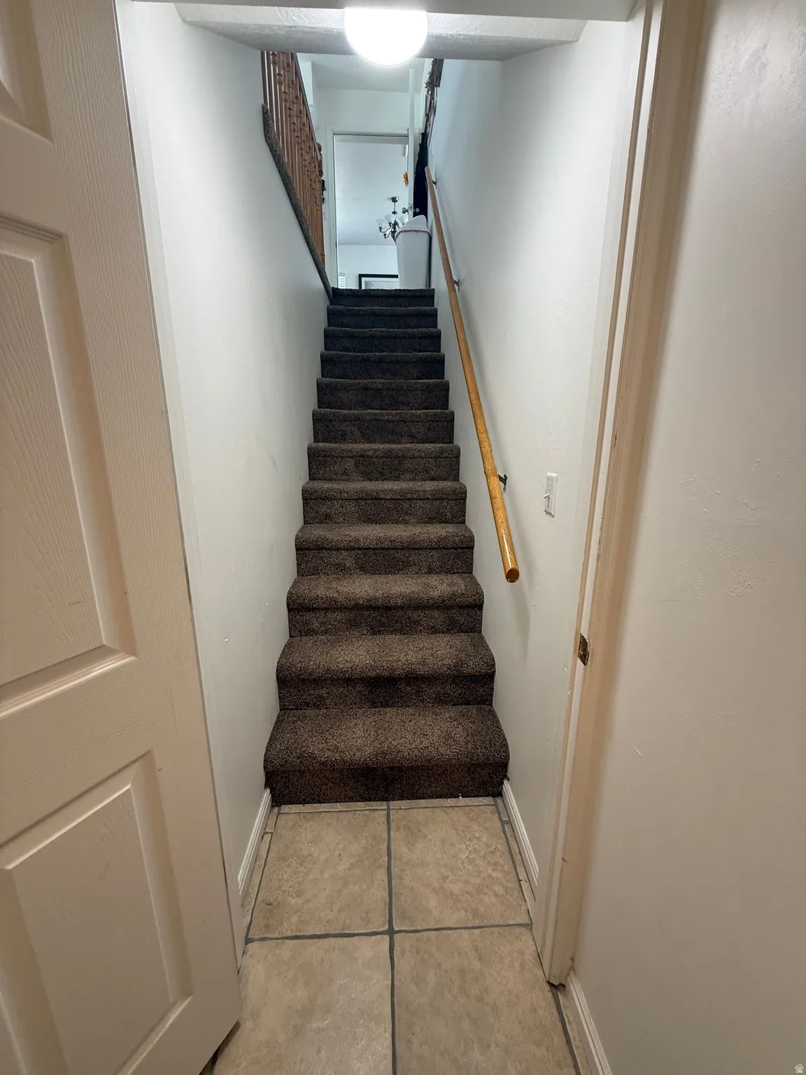 Staircase with baseboards and tile patterned floors