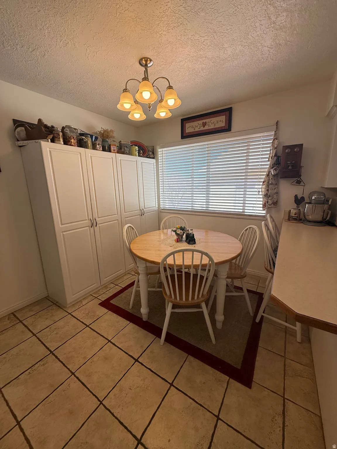 Dining space featuring a textured ceiling, hanging lights, and light tile patterned flooring