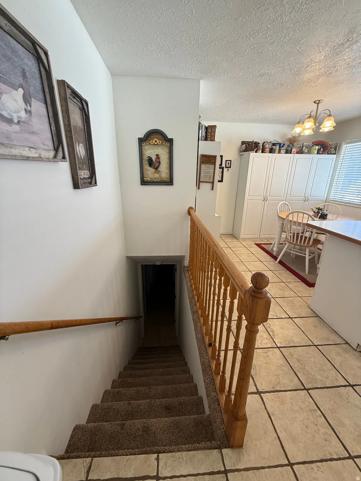 Staircase with suspended lighting, tile patterned floors, and a textured ceiling