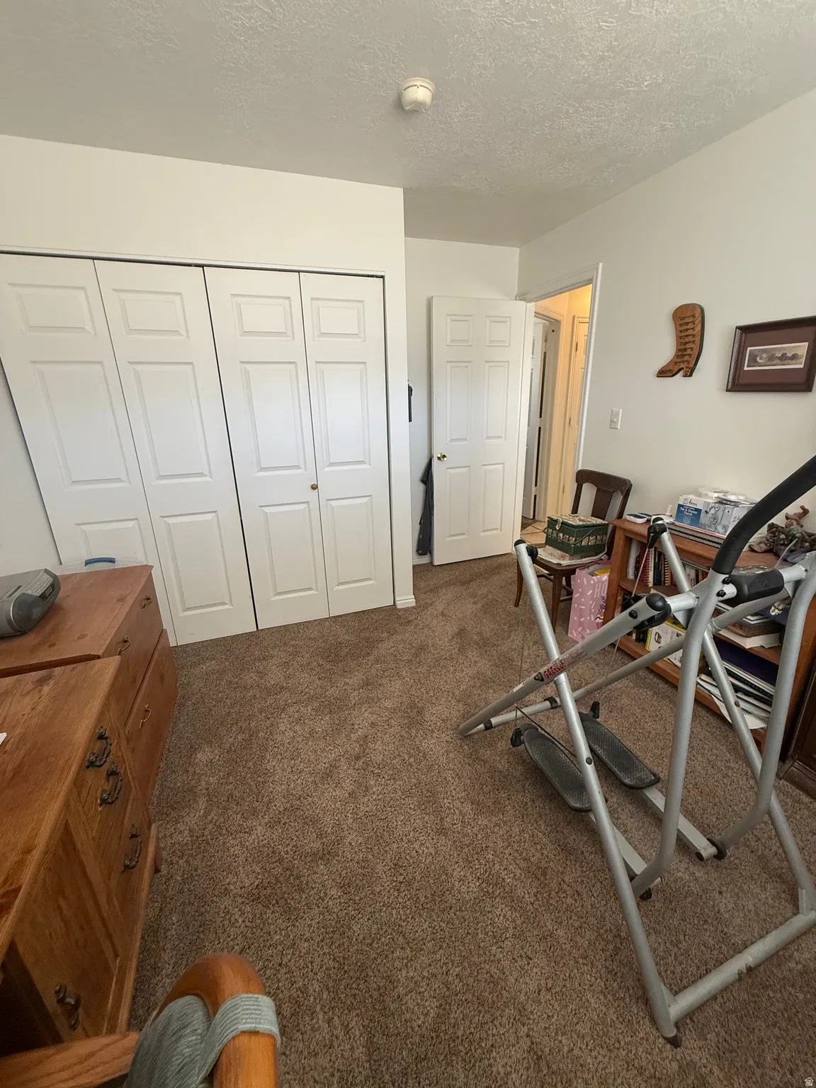 Exercise area with a textured ceiling and dark colored carpet
