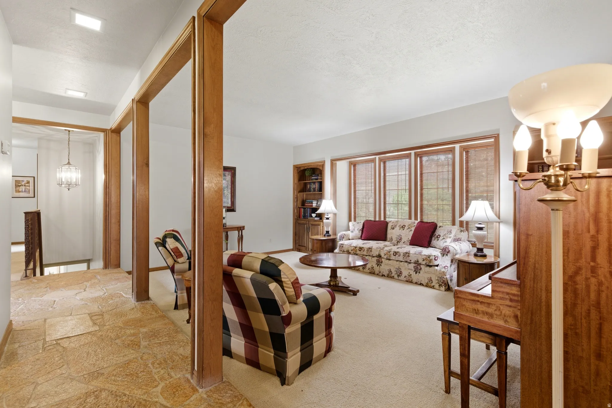 Living room featuring hanging lights, a textured ceiling, and light stone finish floors