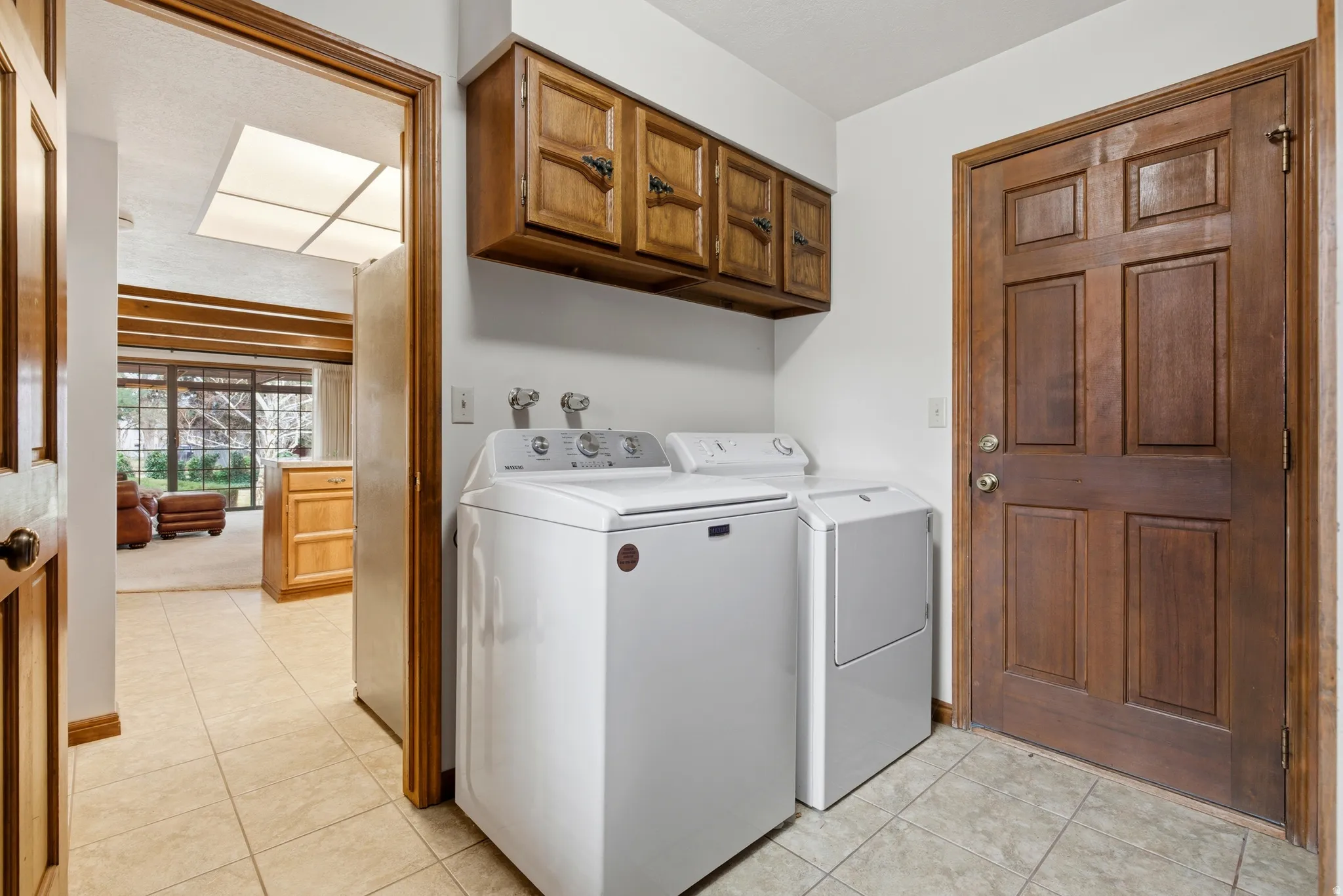 Laundry room featuring light tile patterned flooring, separate washer and dryer, and cabinet space