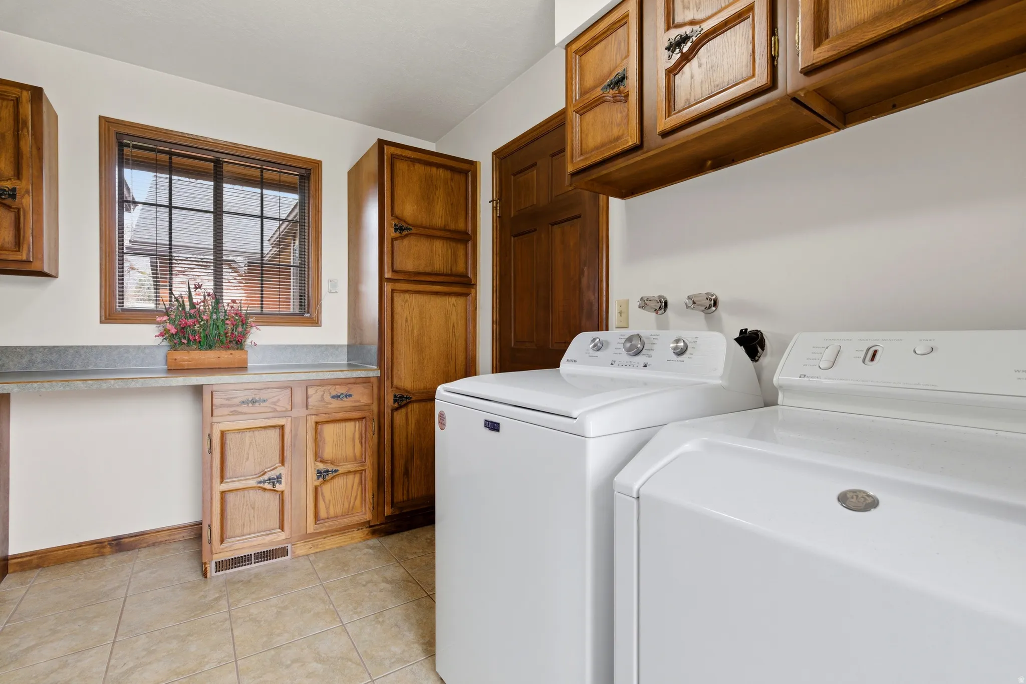 Laundry room with cabinet space, washer and dryer, and light tile patterned floors
