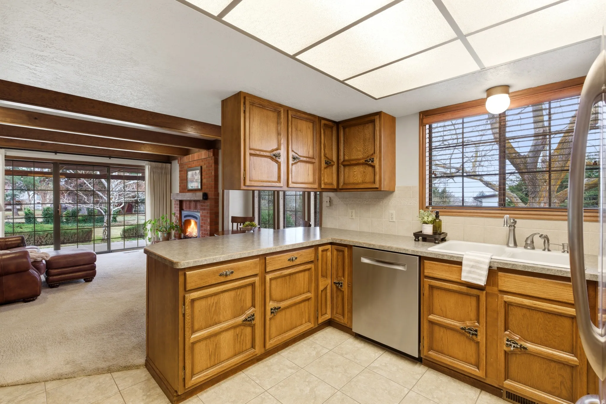 Kitchen with light countertops, wood finish cabinets, tasteful backsplash, a peninsula, and stainless steel appliances