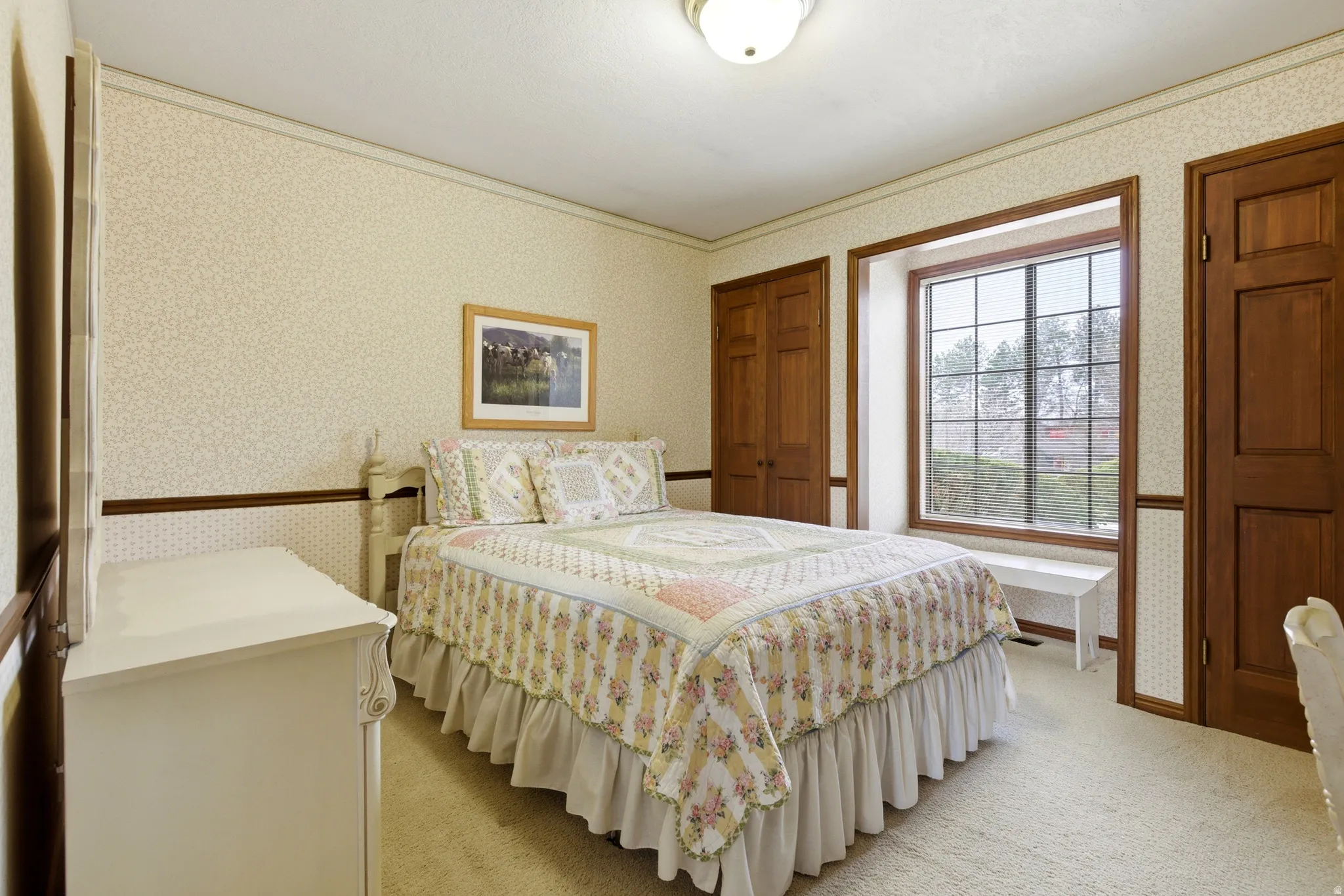 Bedroom with wallpapered walls, light carpet, and ornamental molding