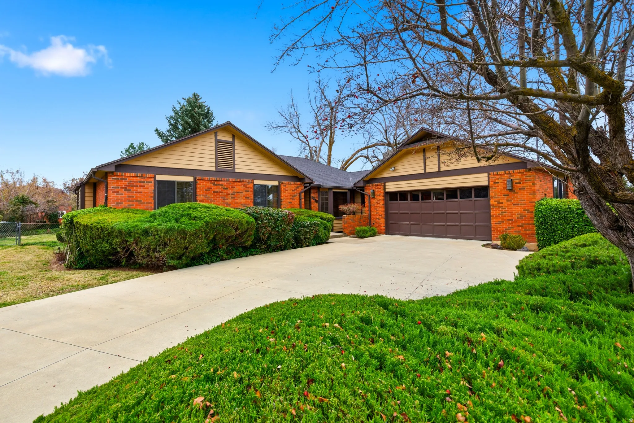 Ranch-style home with concrete driveway, brick siding, and an attached garage