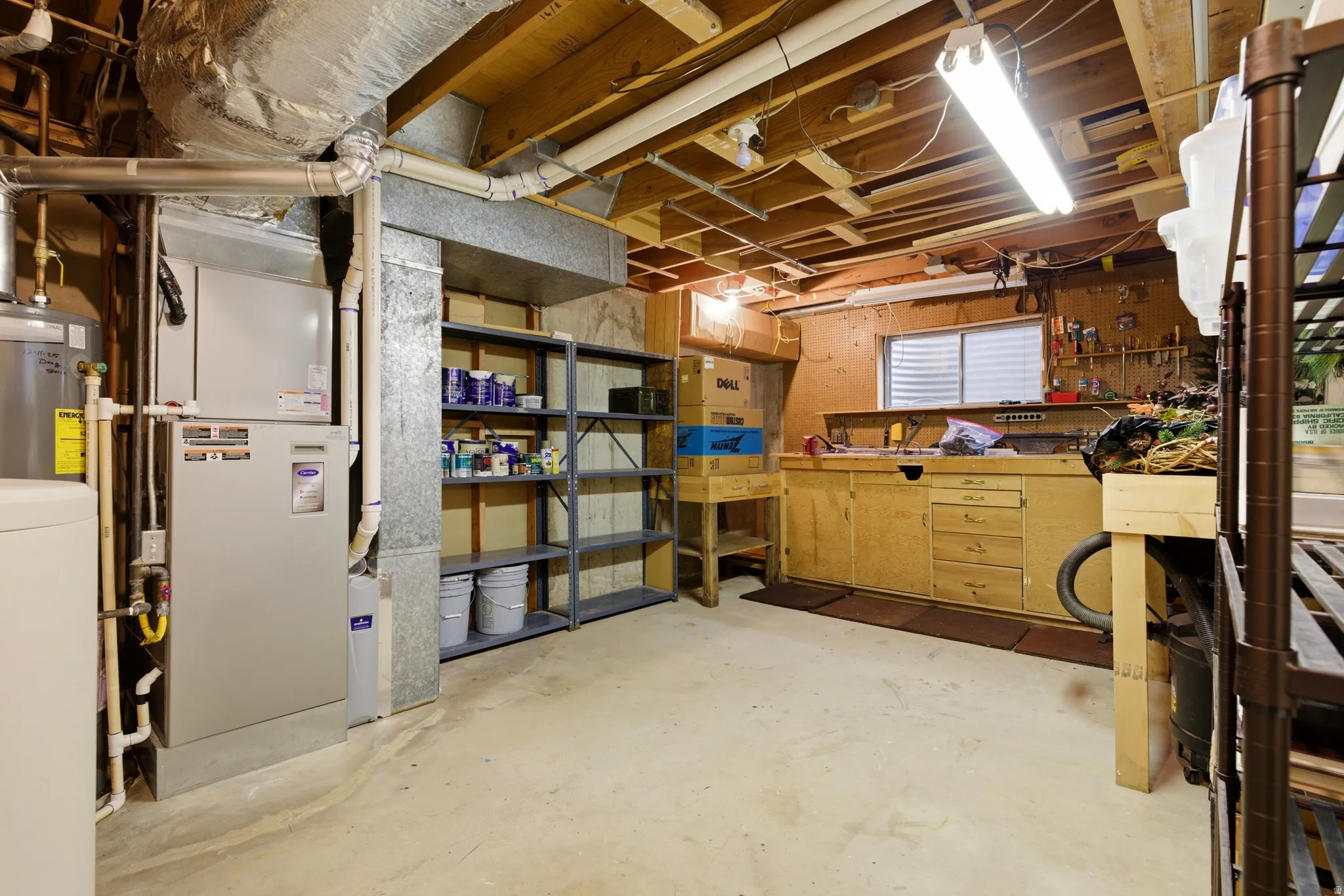 Unfinished below grade area featuring water heater, washer / clothes dryer, and a workshop area