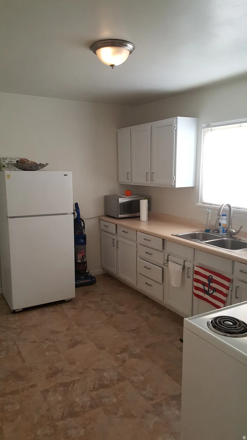Kitchen with white appliances, light countertops, and white cabinetry