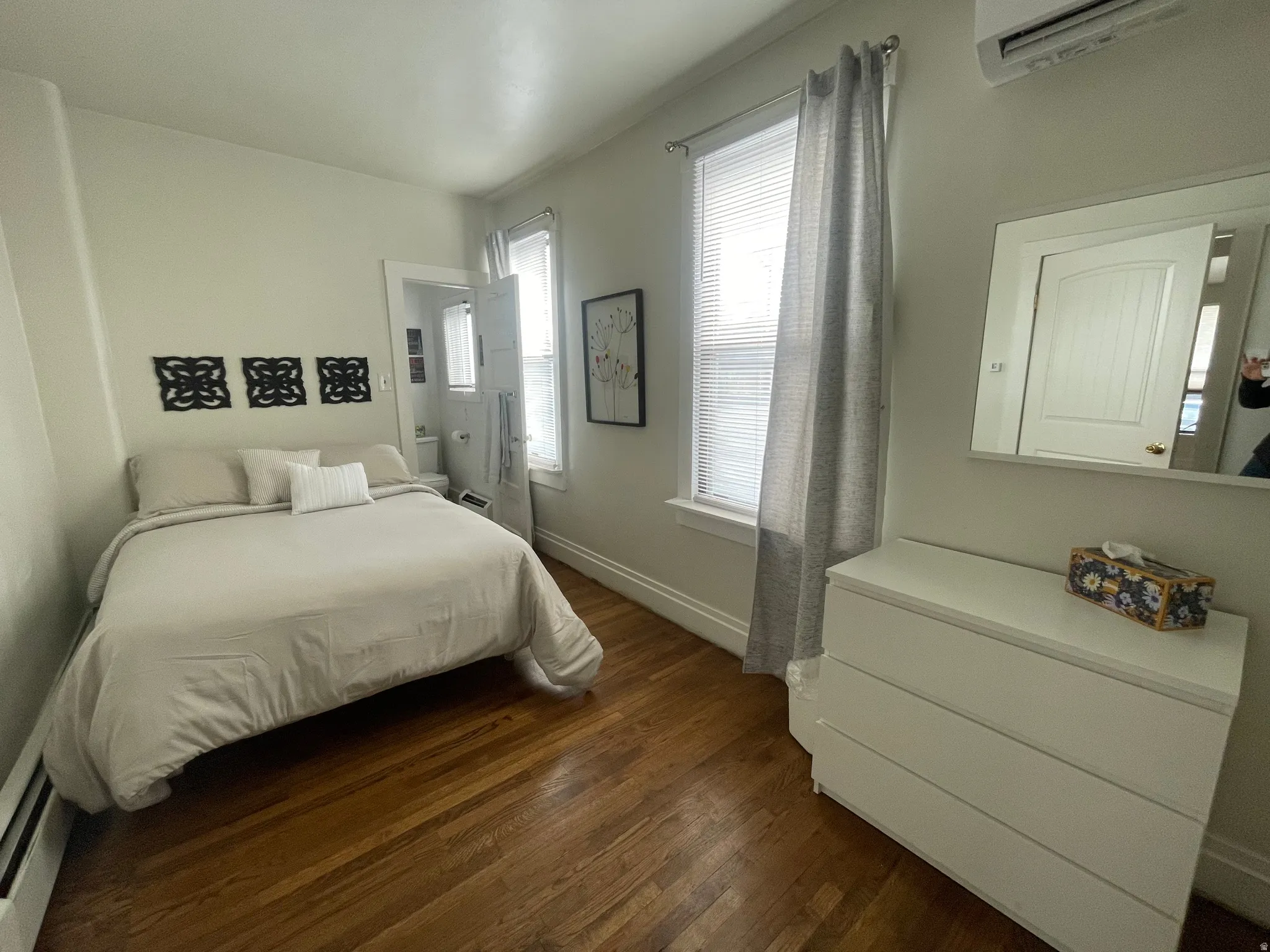 Bedroom featuring dark wood finished floors and an AC wall unit