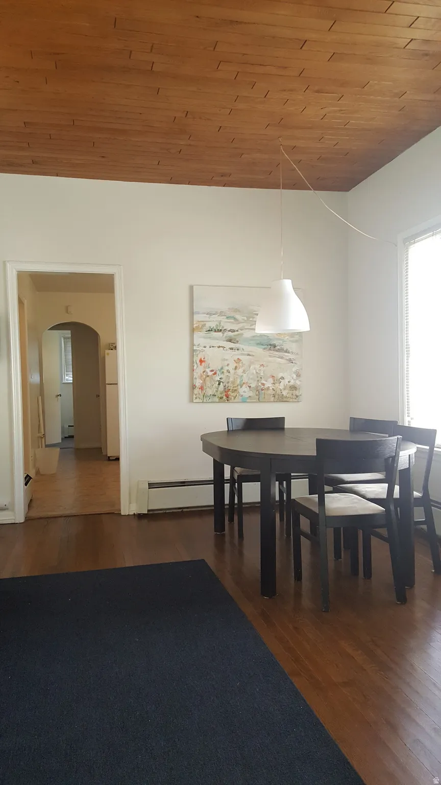 Dining space featuring wooden ceiling, dark wood finished floors, and arched walkways