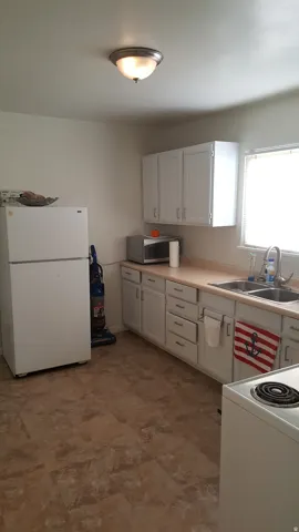 Kitchen with white appliances, light countertops, and white cabinetry
