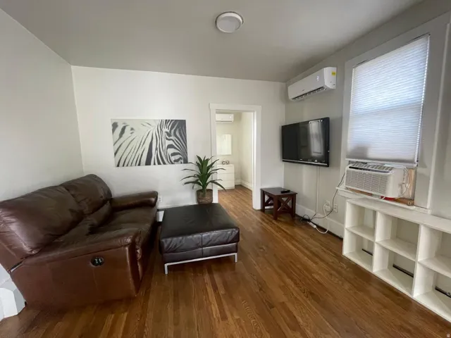 Living room featuring dark wood-style flooring, a wall mounted mini split, and cooling unit