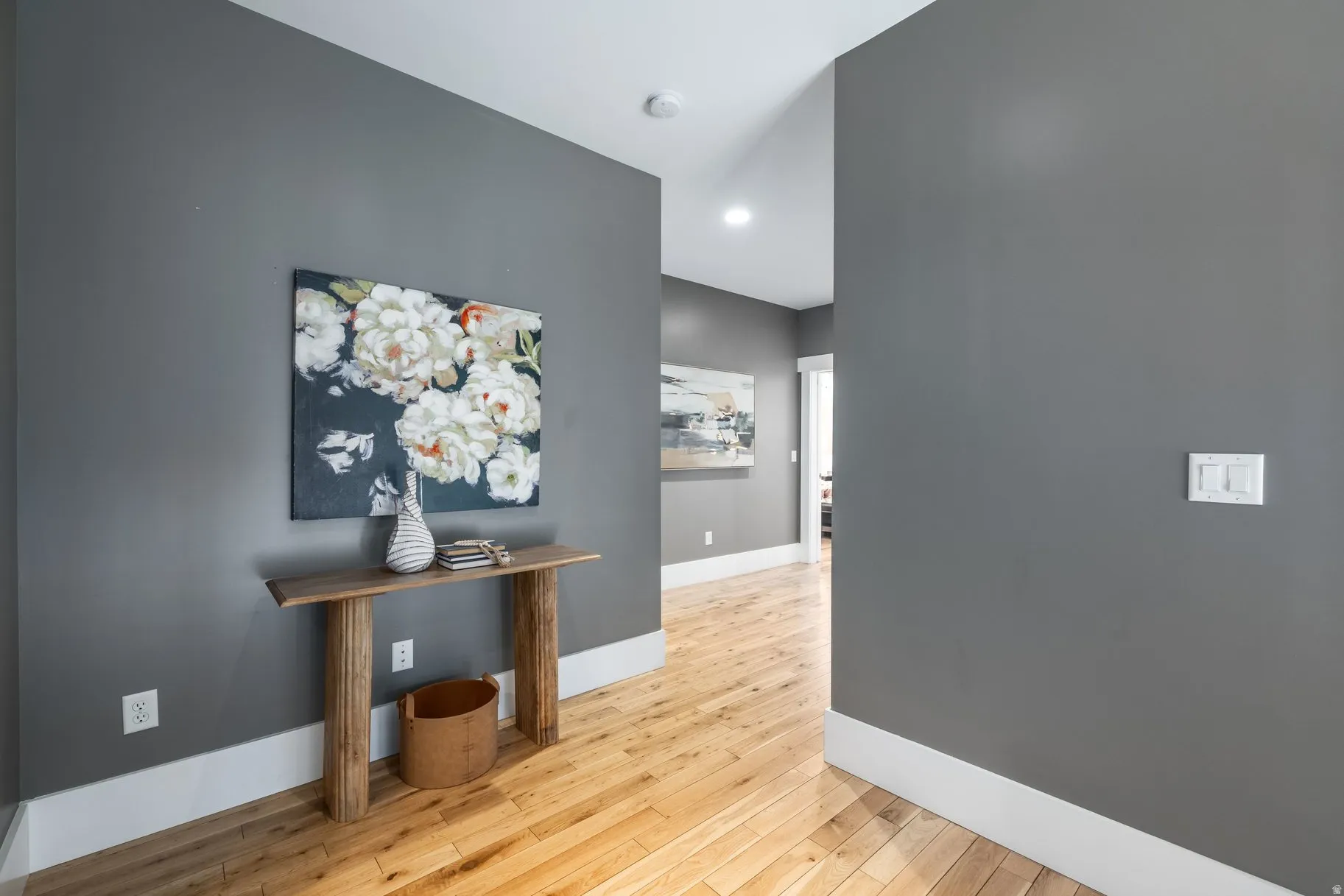 Hall with light wood finished floors and recessed lighting