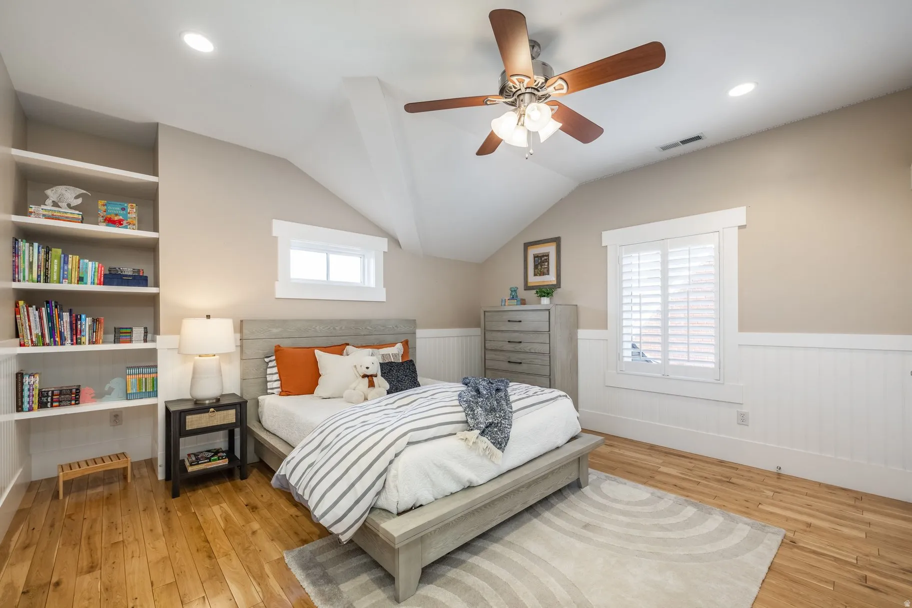 Bedroom with light wood-style floors, a wainscoted wall, lofted ceiling, ceiling fan, and recessed lighting