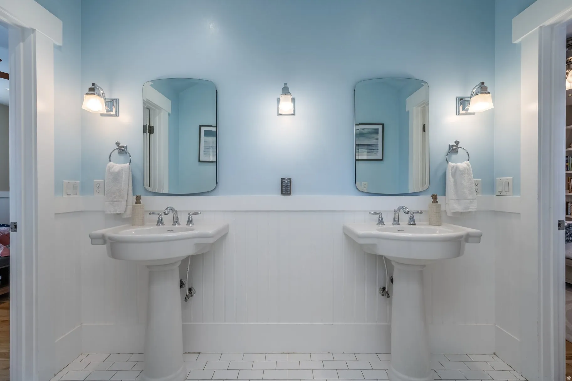 Bathroom with wainscoting, connected bathroom, and two sinks