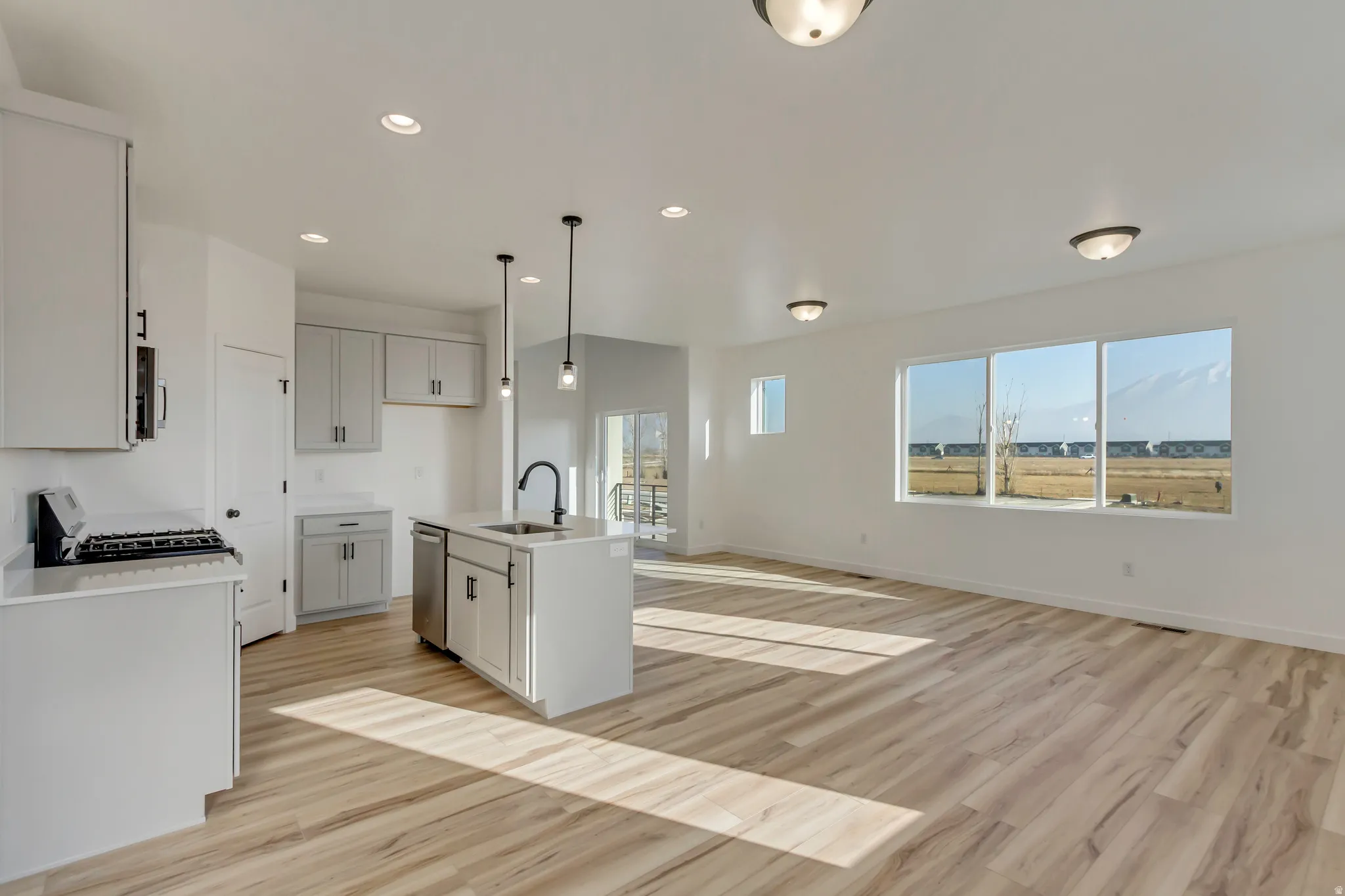 Kitchen with a kitchen island with sink, open floor plan, light wood-style floors, and stainless steel appliances