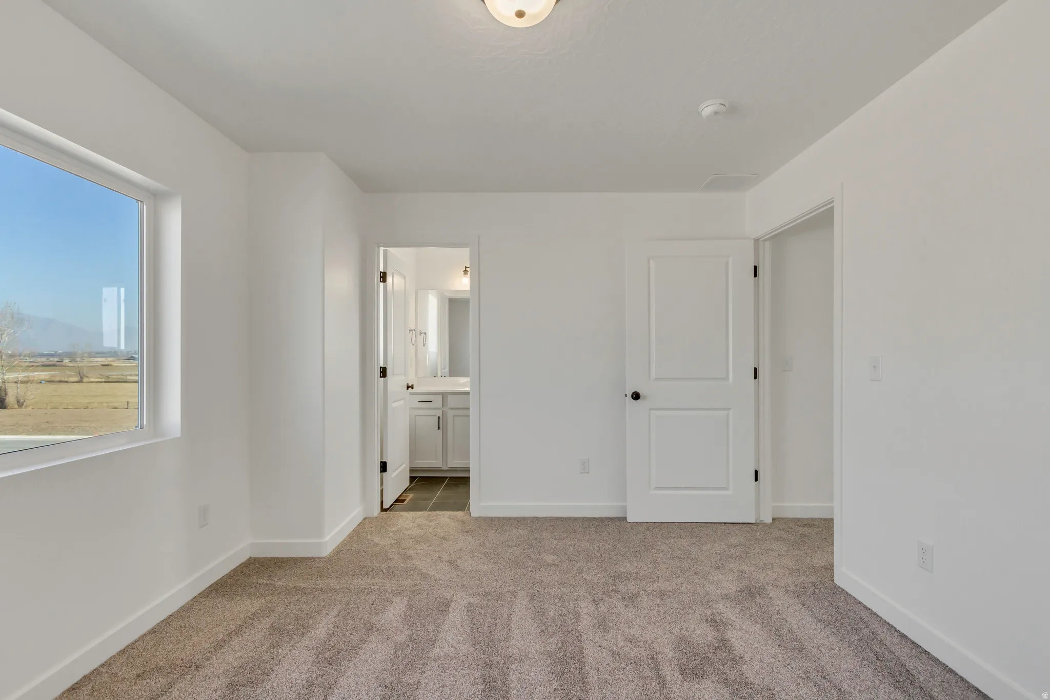 Unfurnished bedroom with ensuite bath and light carpet