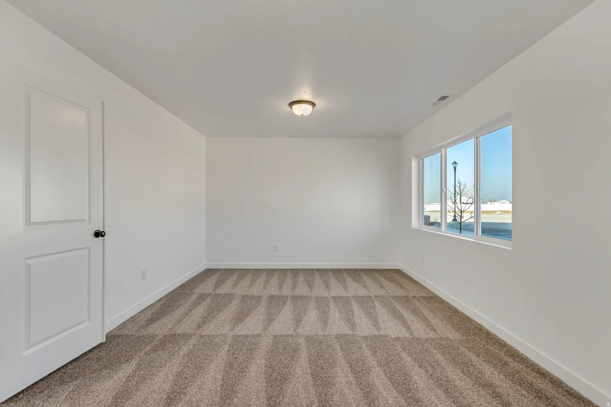 Empty room with baseboards and light colored carpet