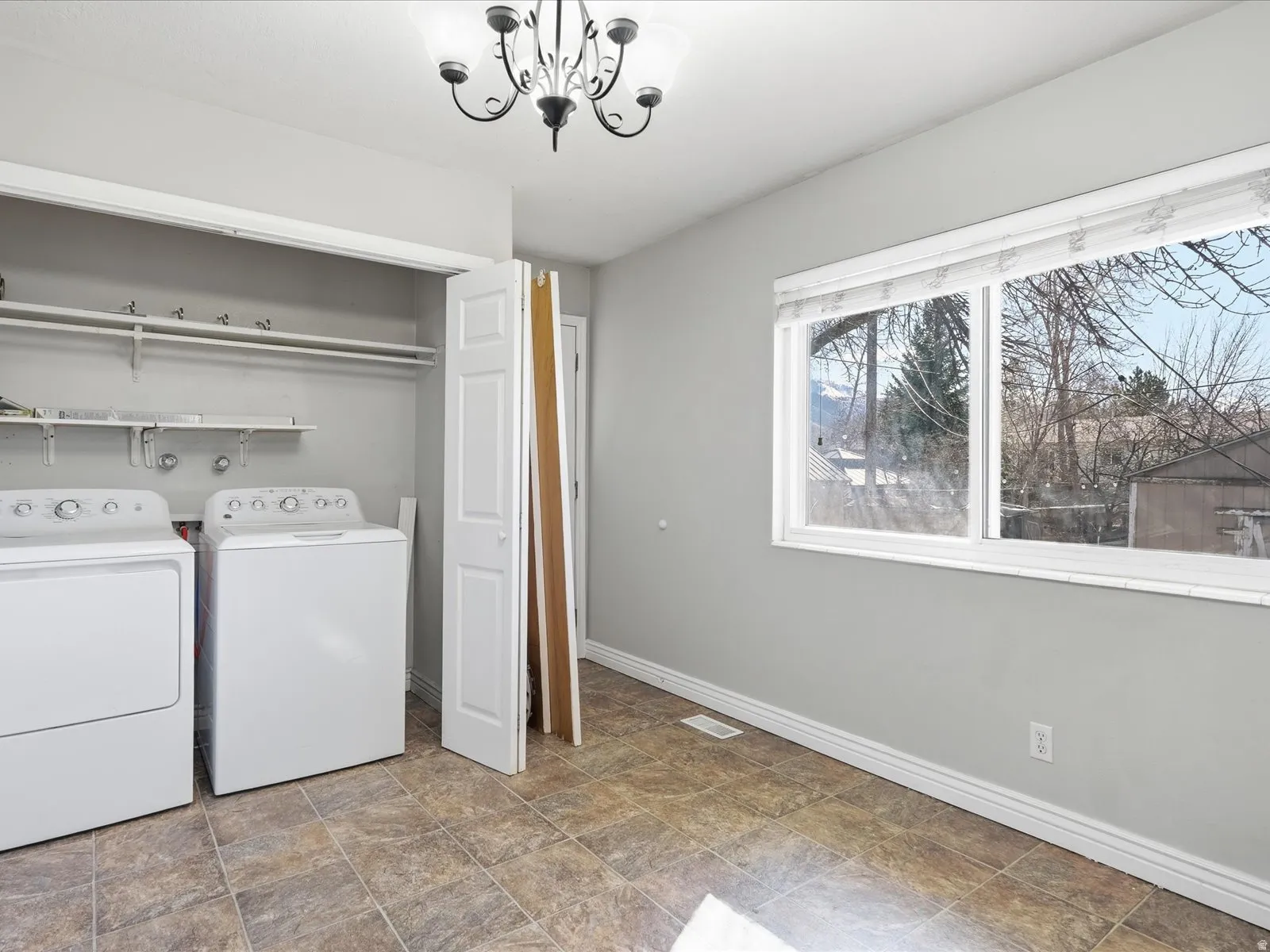 Laundry area featuring stone finish floors, washer and dryer, and a chandelier
