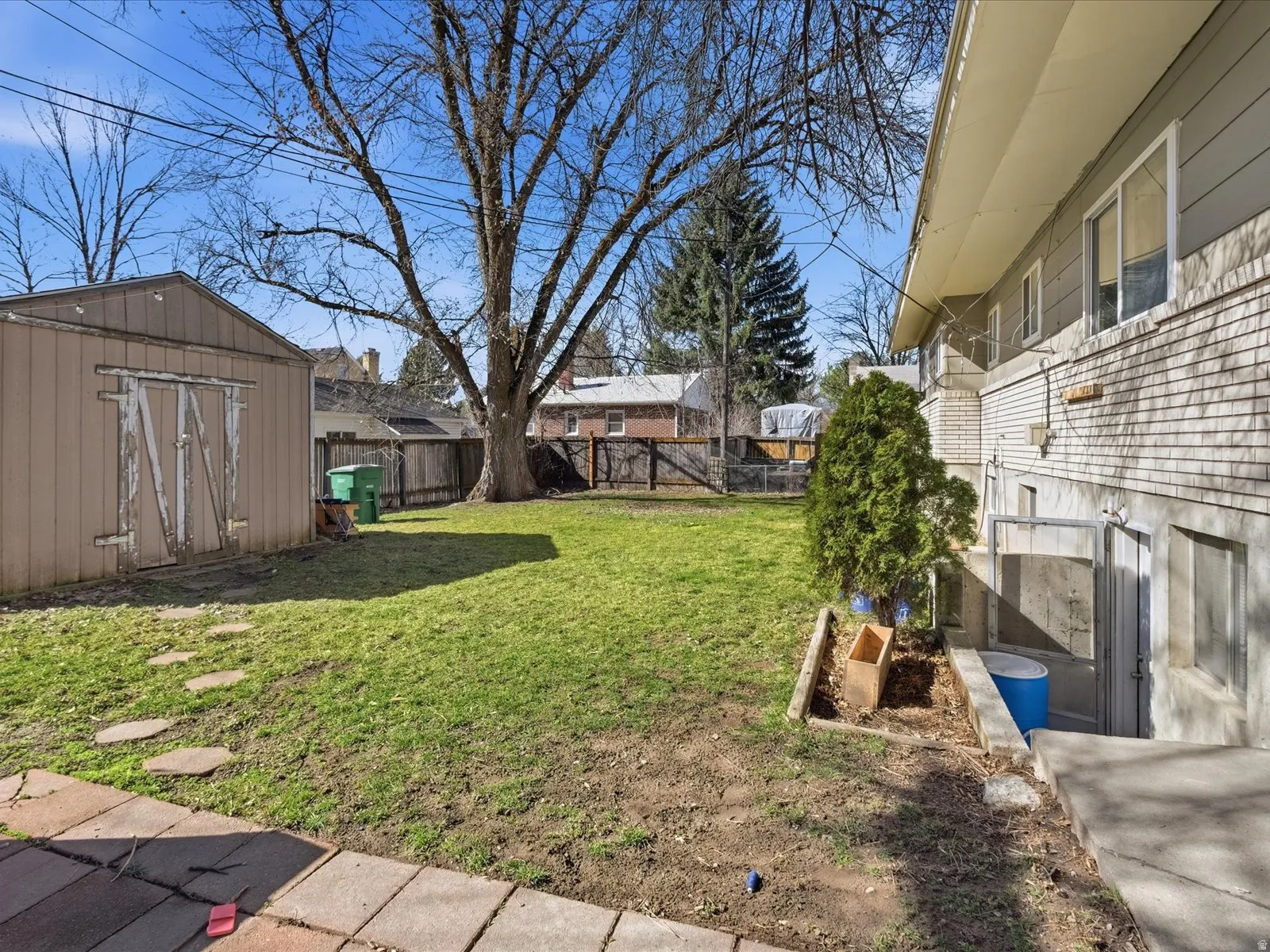 Fenced backyard featuring a storage shed