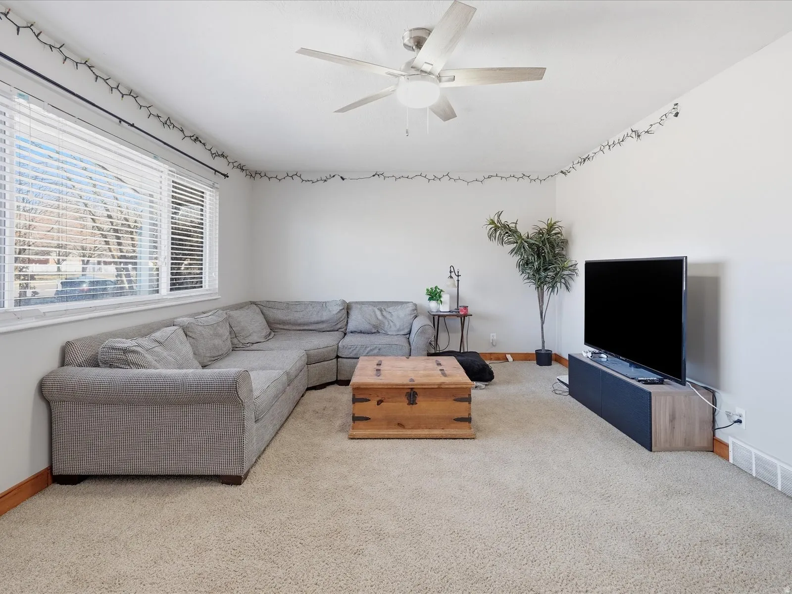 Living area featuring a ceiling fan and light colored carpet