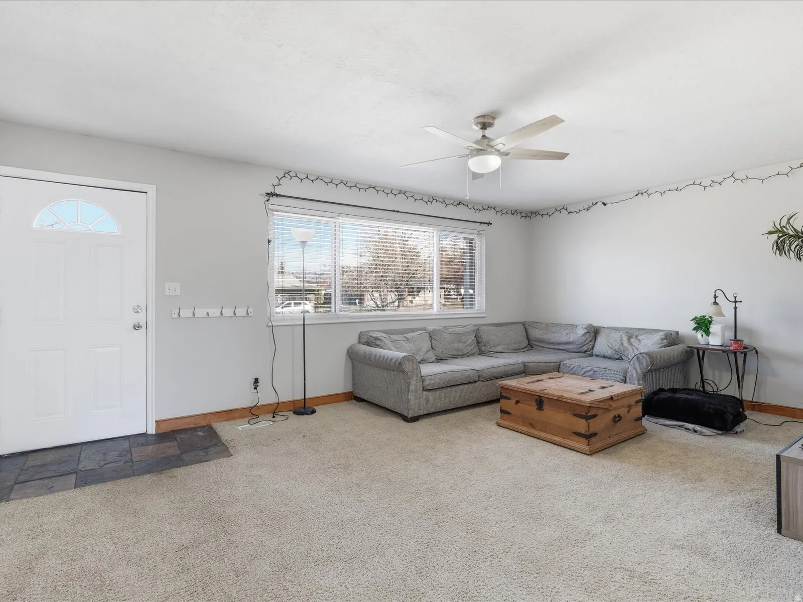 Carpeted living area featuring a ceiling fan and baseboards