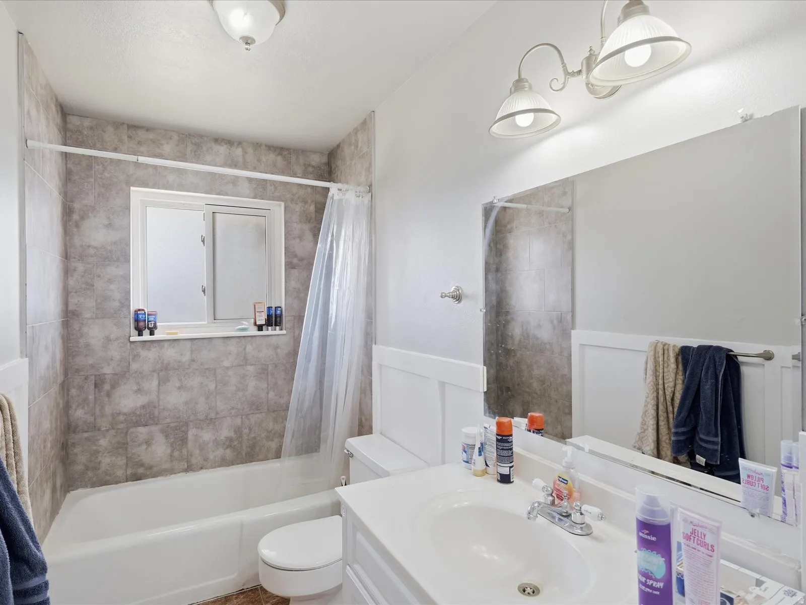 Full bathroom featuring vanity, shower / tub combo, a wainscoted wall, and a decorative wall