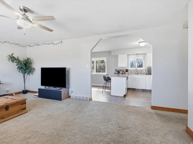 Living room featuring light colored carpet, ceiling fan, and arched walkways