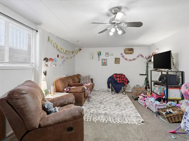 Carpeted living area with ceiling fan