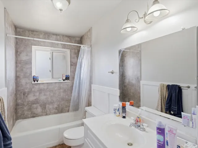 Full bathroom featuring vanity, shower / tub combo, a wainscoted wall, and a decorative wall