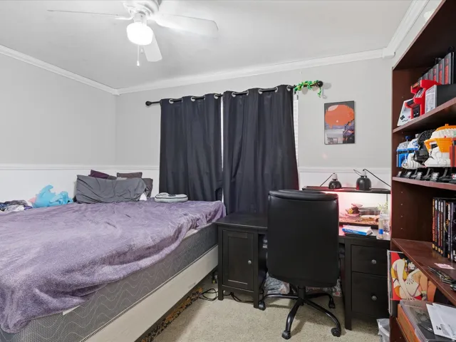 Bedroom featuring light colored carpet, crown molding, and ceiling fan
