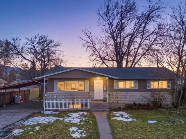 View of front of house with covered porch, a lawn, concrete driveway, and an attached carport