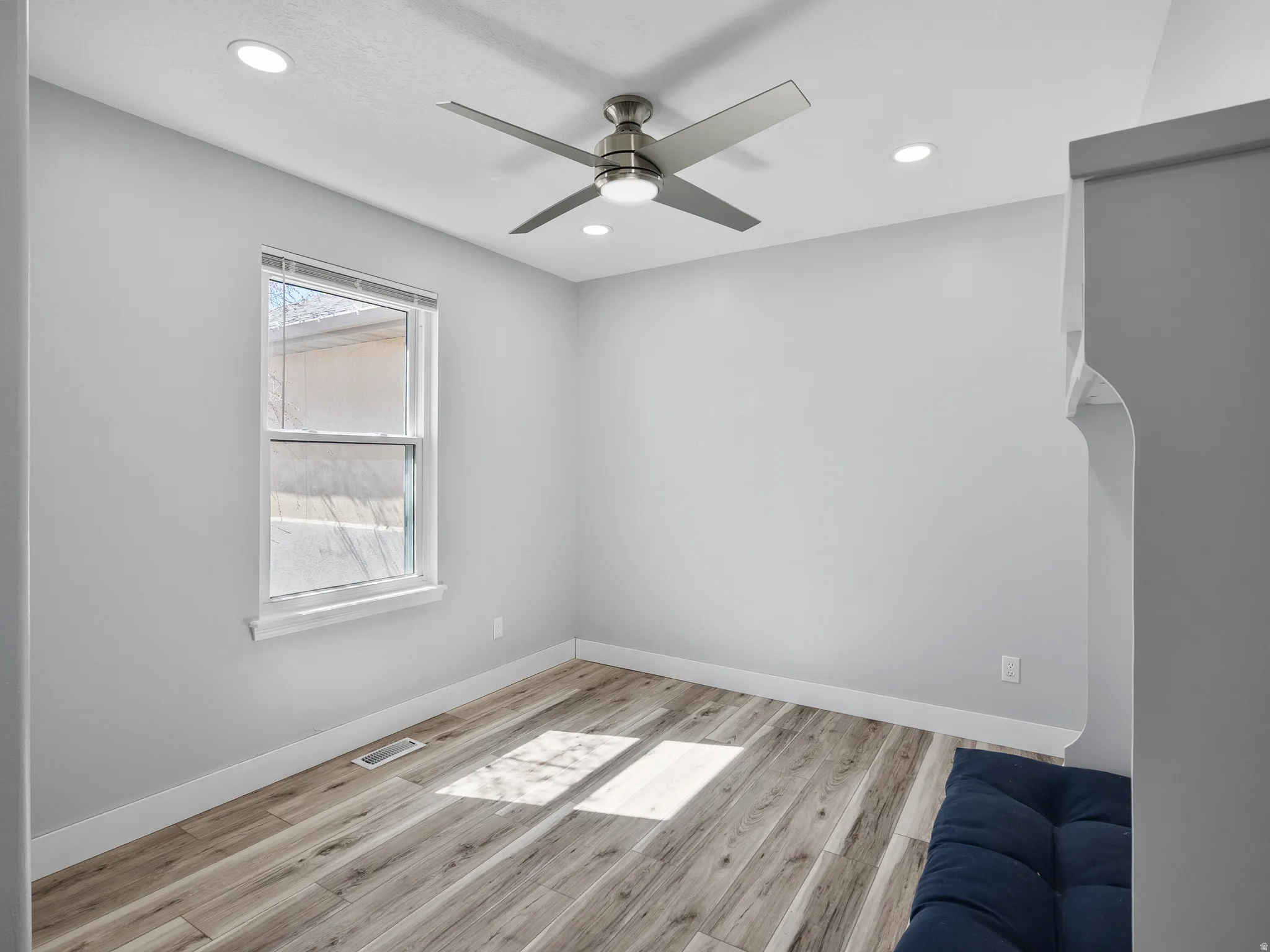 Spare room featuring light wood-type flooring, ceiling fan, and recessed lighting