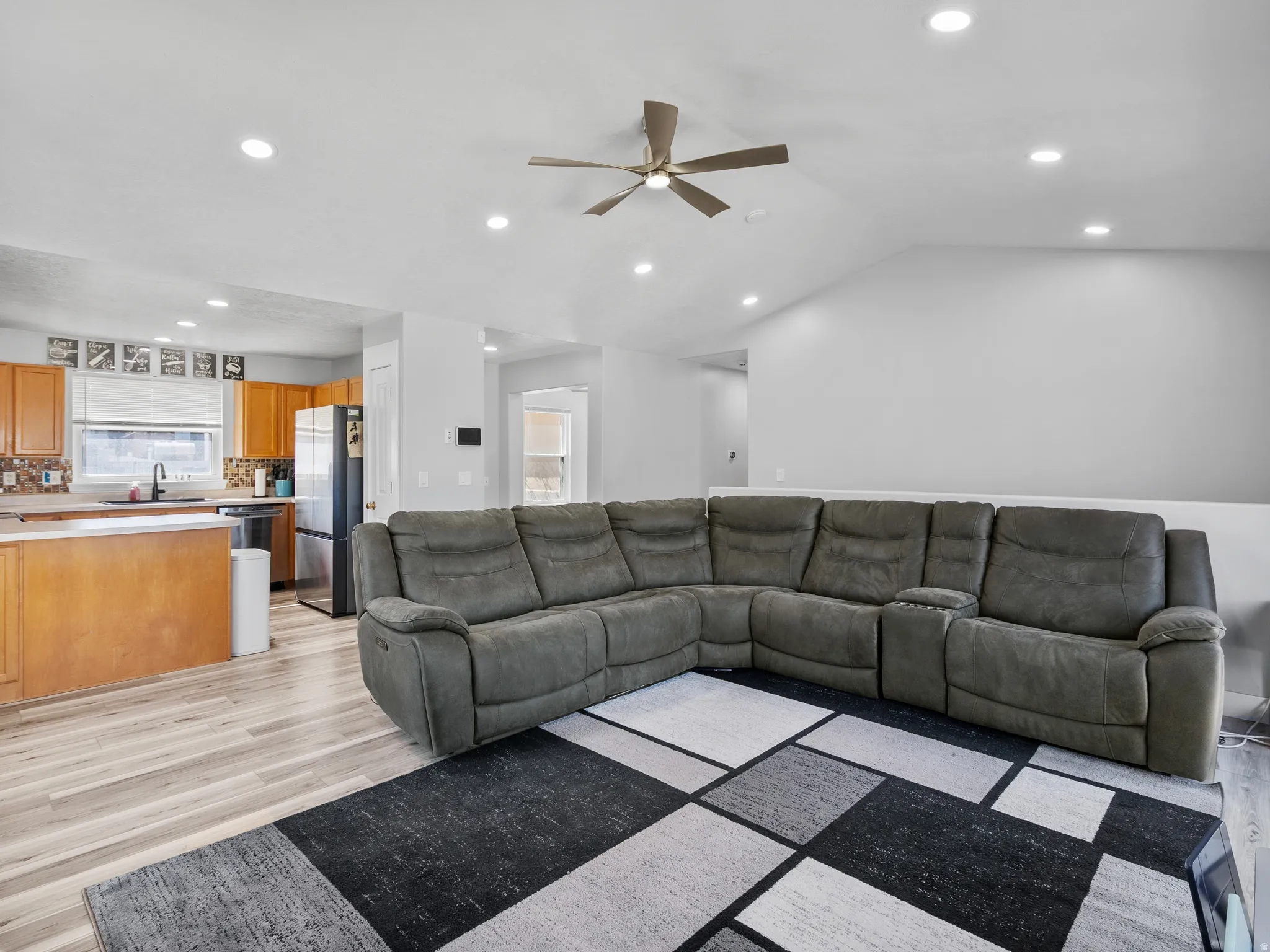Living room featuring light wood-style flooring, a ceiling fan, recessed lighting, and lofted ceiling